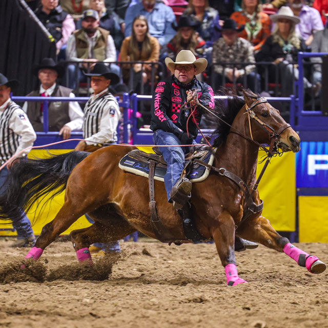 A cowboy riding a horse at a rodeo.